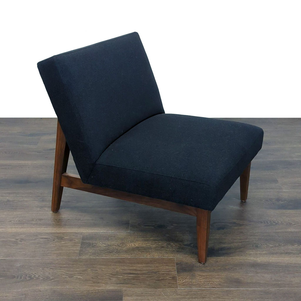 3. Angled view of a Room & Board lounge chair featuring a dark upholstered seat and wooden legs on wood flooring.