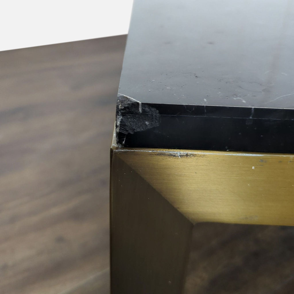 2. Detail of a damaged corner on the Parsons Black Marble coffee table with a brass frame leg.