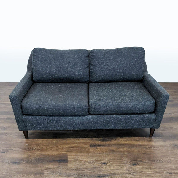 1. Front view of a dark gray West Elm loveseat with two seat cushions, set on a wood floor.  