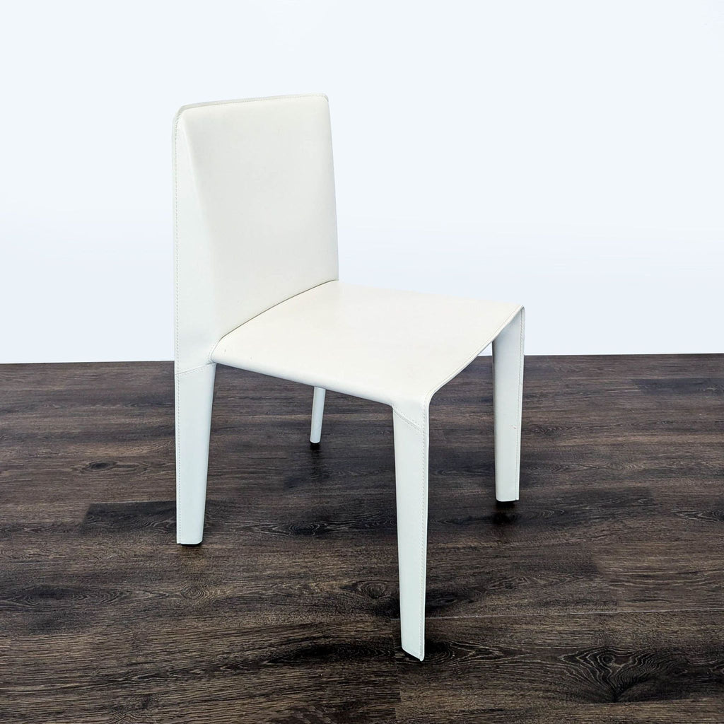 2. Side angle of a minimalist white B&B Italia chair with clean lines and smooth upholstery, on wood flooring.