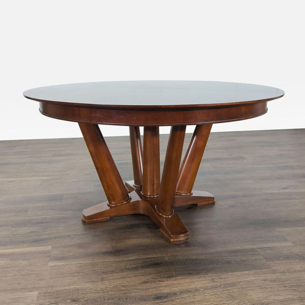 1. Round wood dining table with unique angled legs, by Mitchell Gold + Bob Williams, on hardwood floor.