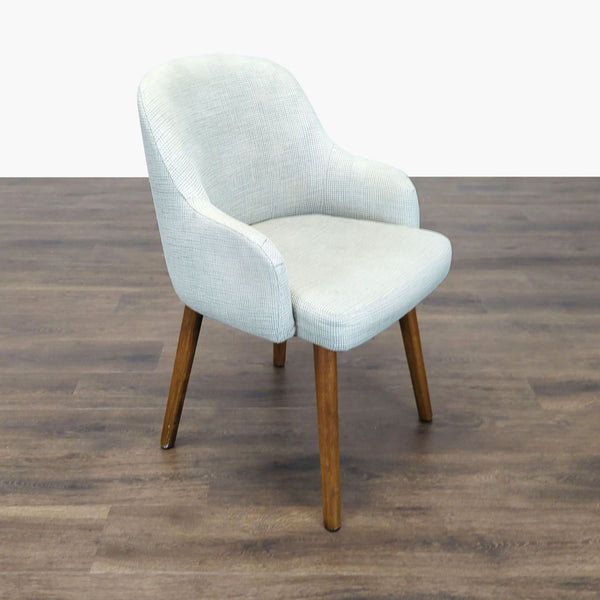 1. West Elm dining chair with light patterned upholstery, curved backrest, and wooden legs on a wood floor.