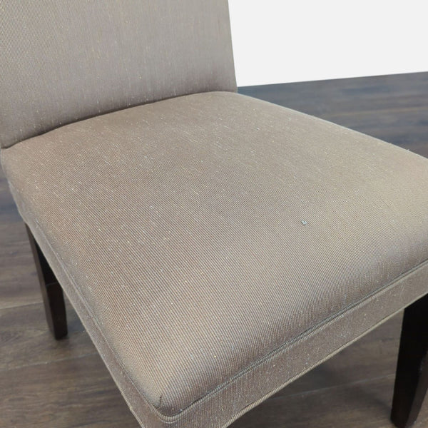 1. Close-up of a taupe upholstered dining chair seat and backrest by Mitchell Gold + Bob Williams.