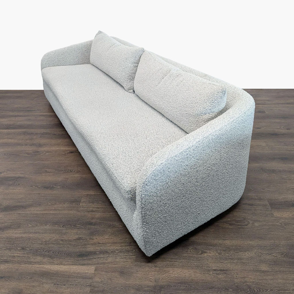 3. Angled view of a modern, light gray 3-seat sofa by Four Hands on a wooden floor.