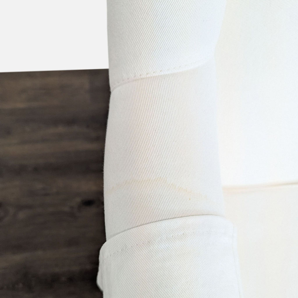 3. Detail of an Ethan Allen lounge chair armrest with white fabric cover, highlighting material texture and slight discoloration.