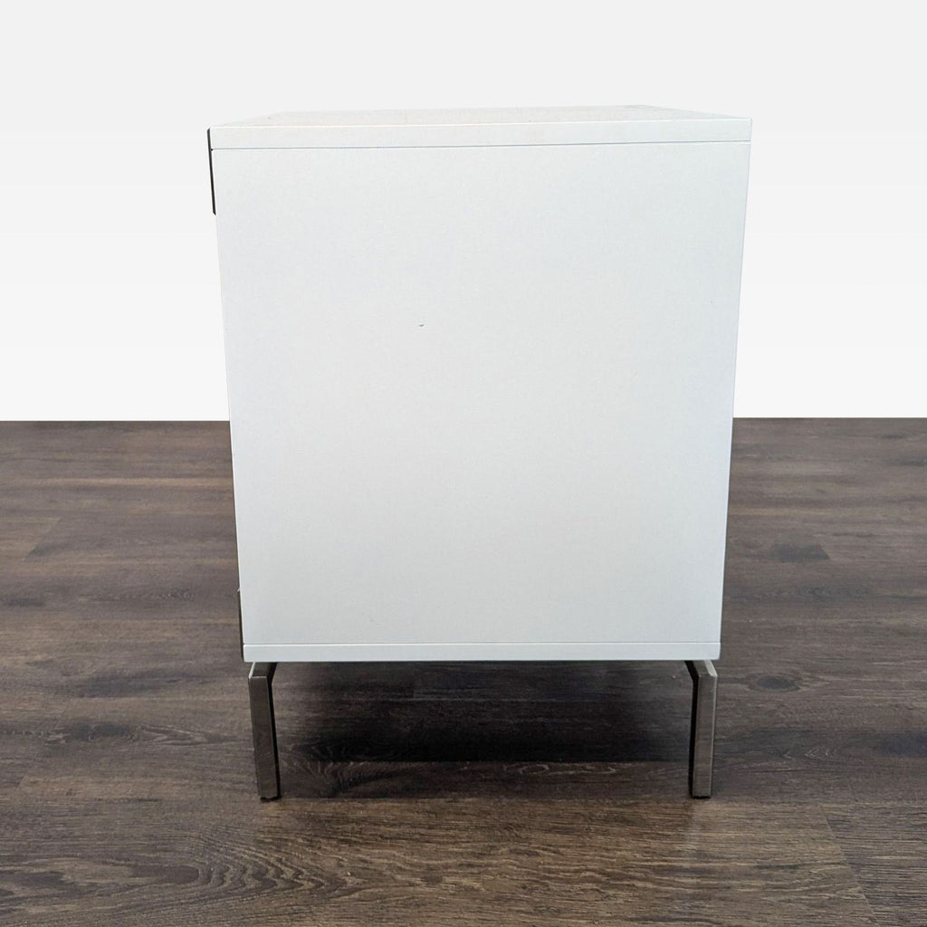 Side view of the West Elm Malone Campaign Nightstand, showing simple white lacquer finish and metal legs.  