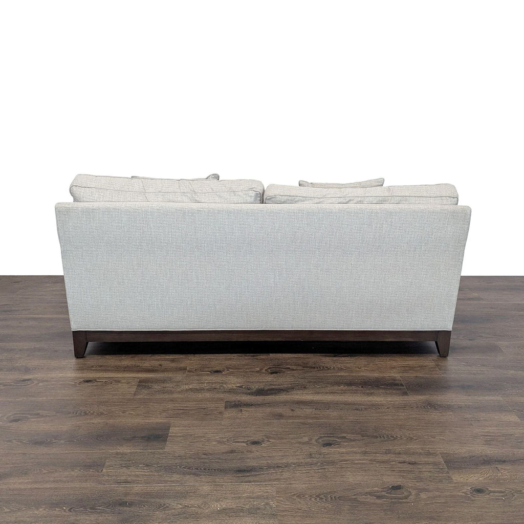 2. Rear view of an Ethan Allen 3-seat sofa in light gray fabric, showing its straight back and dark wood base.  