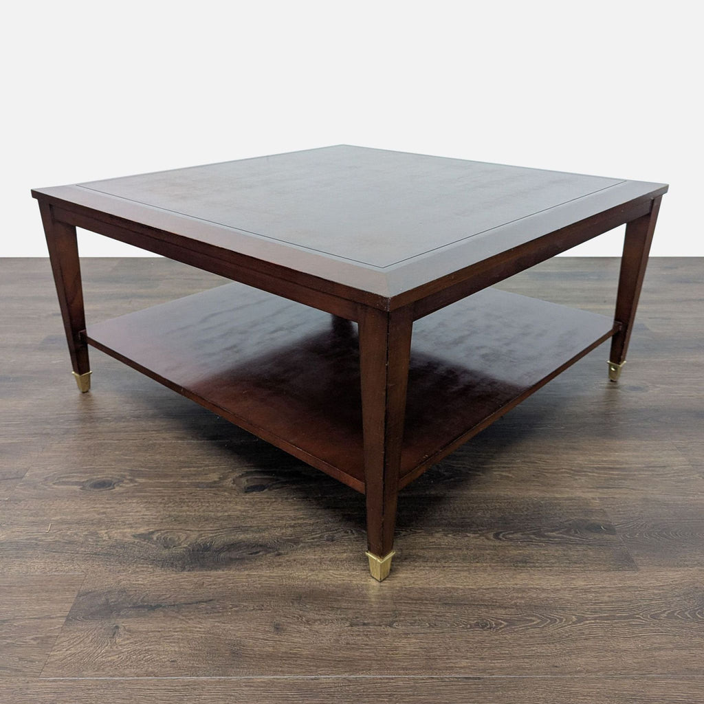 3. Side perspective of a square Reperch coffee table, dark finish, storage shelf below, and brass feet detail.