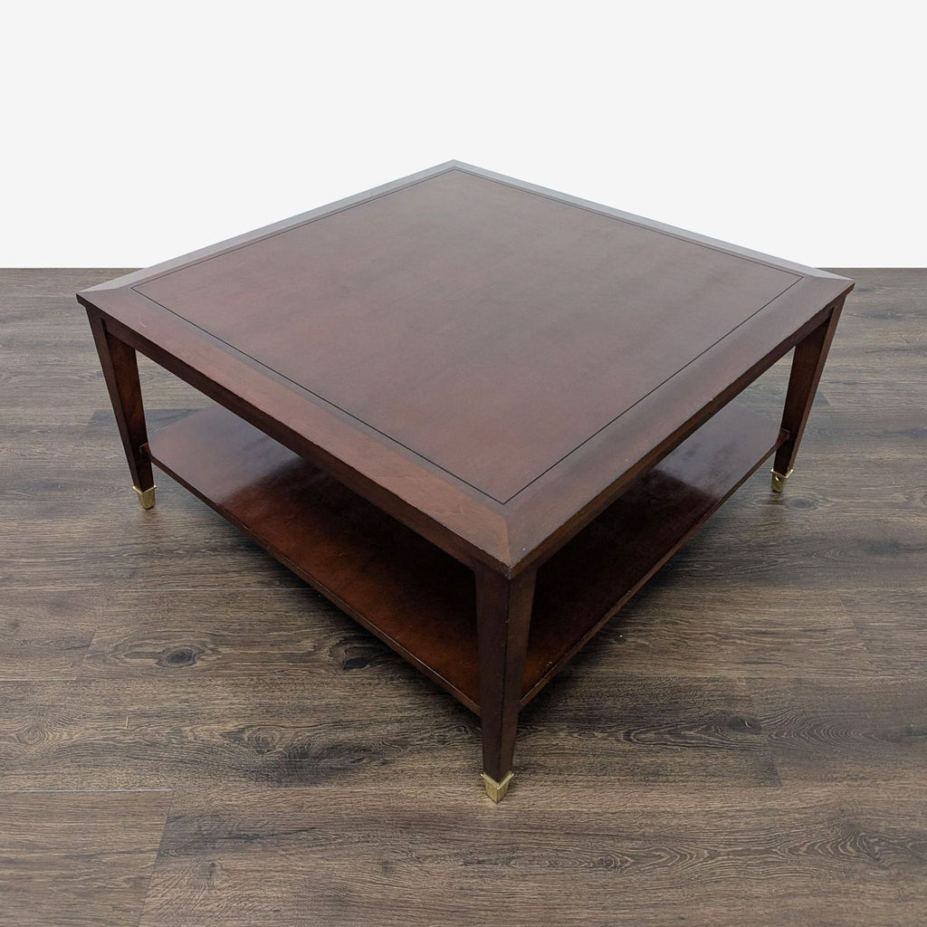 2. Angled view of a wooden Reperch coffee table with a shelf underneath and brass leg accents.  
