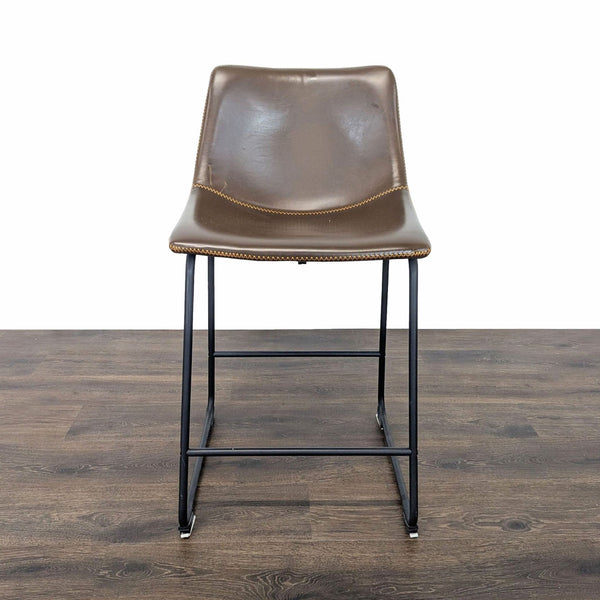 1. Brown leather Reperch stool with black metal legs, viewed from the front, on a wood floor.