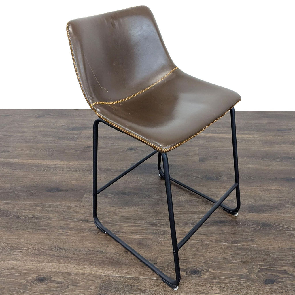 3. Angled view of a Reperch brown faux leather stool with stitched edges and sturdy metal base.