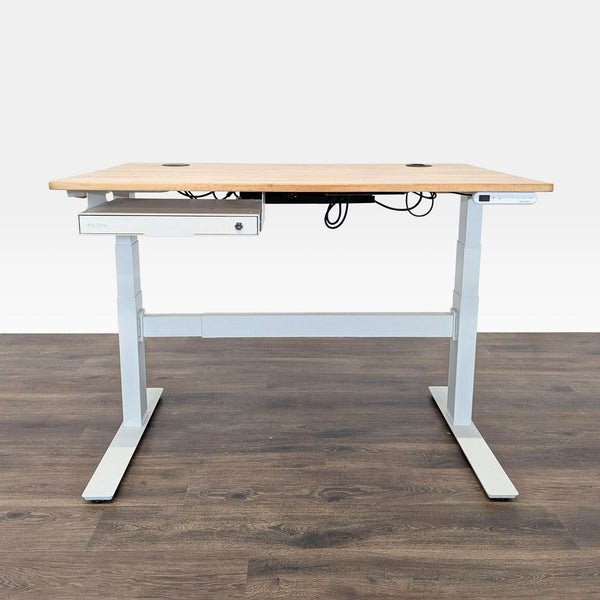 1. Uplift sit-stand desk with a light wood top, white frame, cable management, and under-desk storage on a dark floor.  