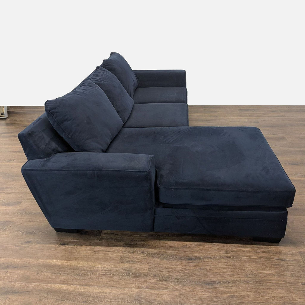 2. Side view of a Living Spaces sectional showing soft cushions, track arms, and reversible chaise seating.