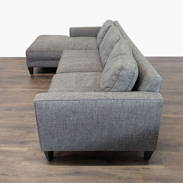 1. Side view of a Room and Board sectional sofa in gray fabric, showing modern lines and wood legs.  