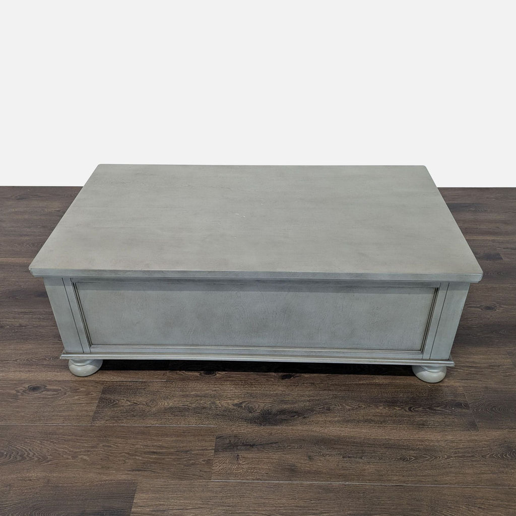 2. Rear view of Reperch Coffee Table, gray wood with paneled detailing and rounded feet, no visible handles.