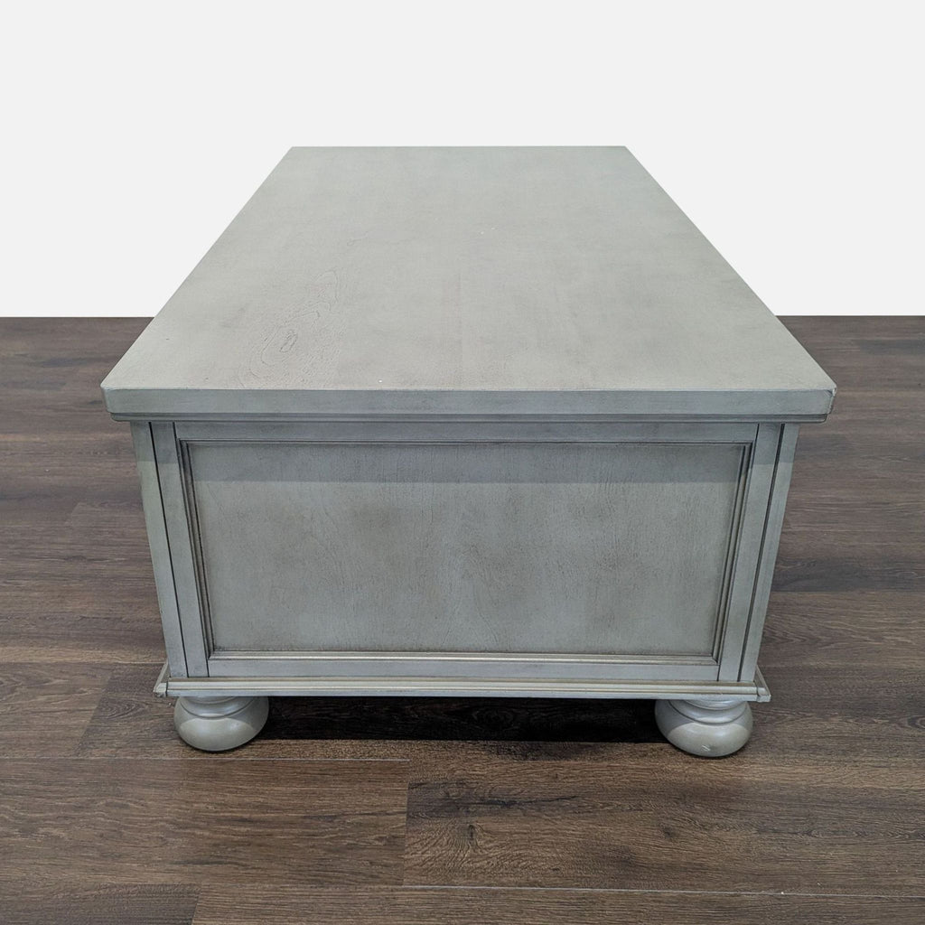 3. Side view of Reperch Coffee Table, gray wood construction with simple trim and turned feet, modern classic style.
