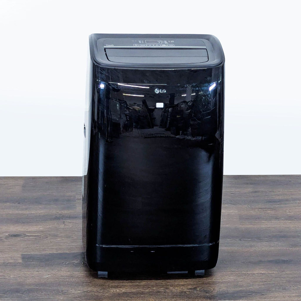 1. Front view of a sleek black LG portable air conditioner with top controls, ideal for cooling small rooms.