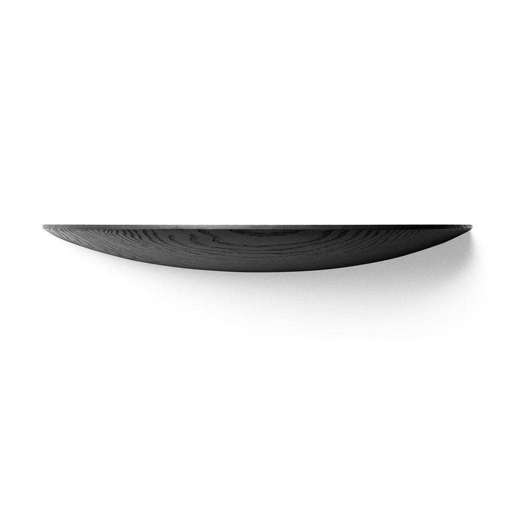 Audo Copenhagen Black Oak item shown from the side, displaying a curved, minimalist wooden design against a white background.  
