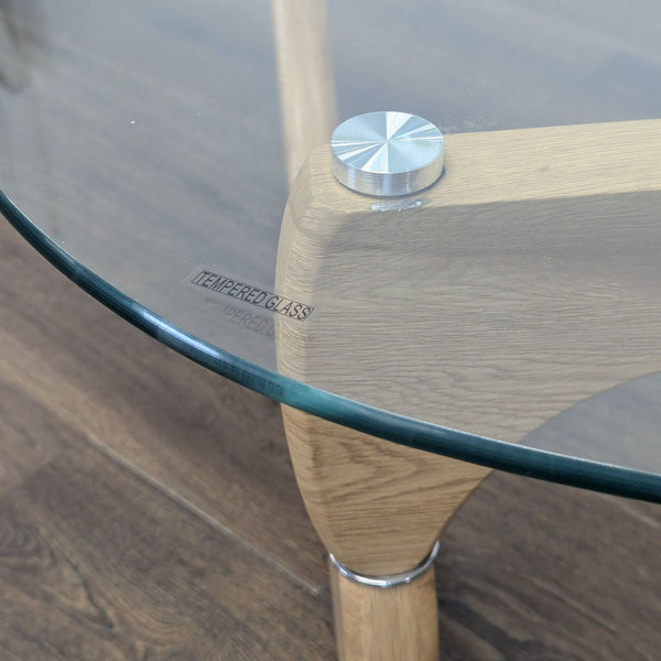 1. Close-up of a Reperch coffee table corner showing tempered glass top and light wood leg joined by a metal fastener.