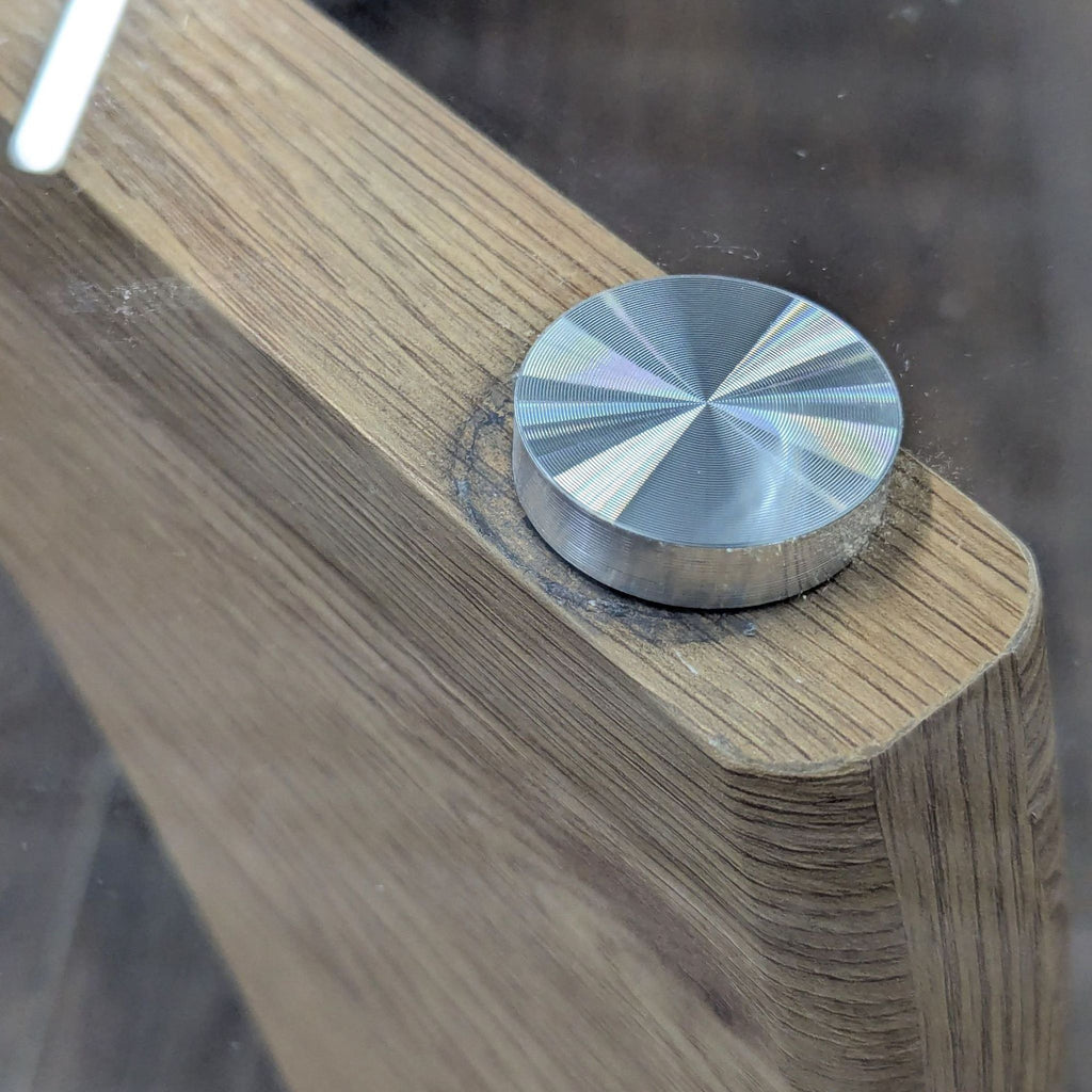 2. Detailed image of a brushed metal fastener connecting the glass surface to a wooden Reperch coffee table frame.