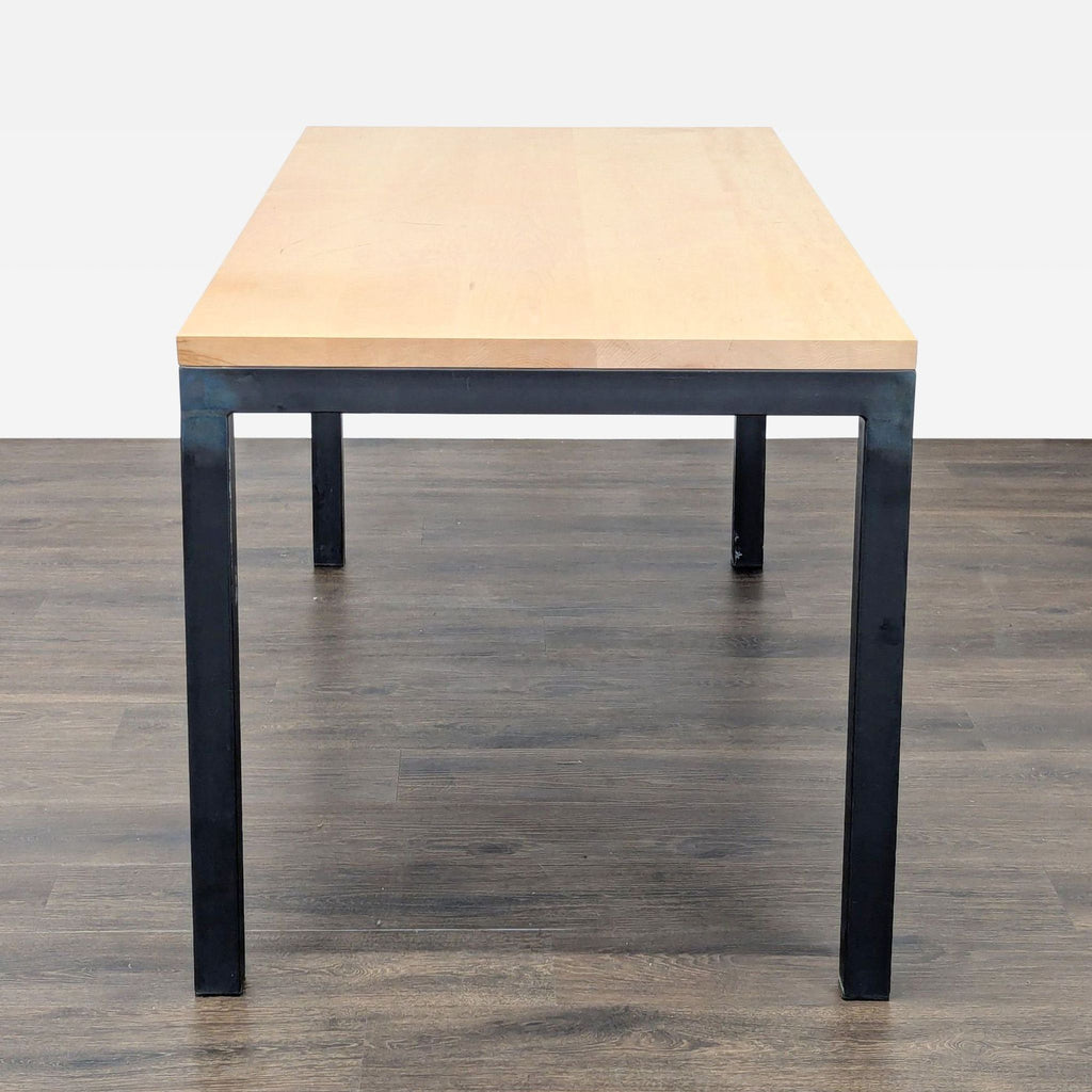 Room & Board dining table featuring a maple tabletop and sturdy natural steel base, viewed from the end.  