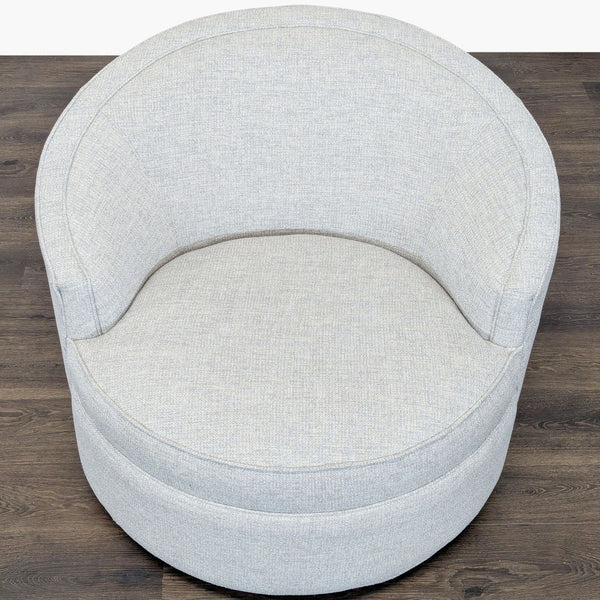 1. Top view of a round, light gray lounge chair by Reperch with soft fabric and curved backrest on wood floor.  