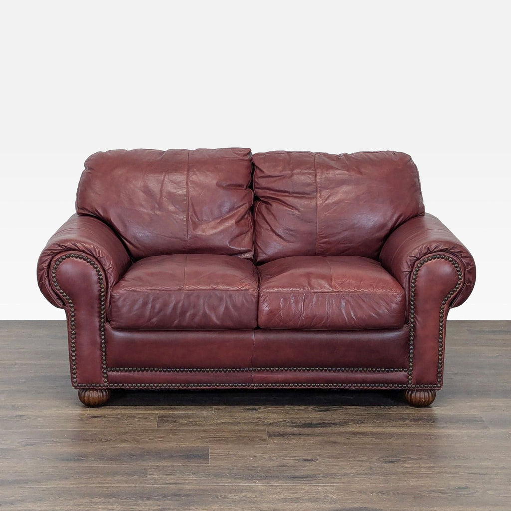 1. Front view of a classic leather loveseat by Viewpoint Leather Works, featuring rolled arms and studded accents.  