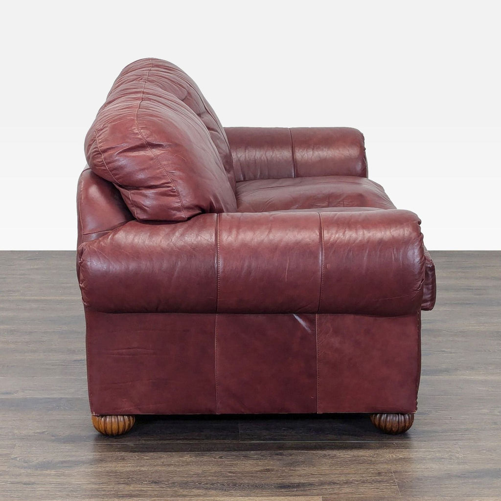 2. Side view of a brown leather loveseat with deep cushions and sturdy wooden feet, perfect for living rooms.  