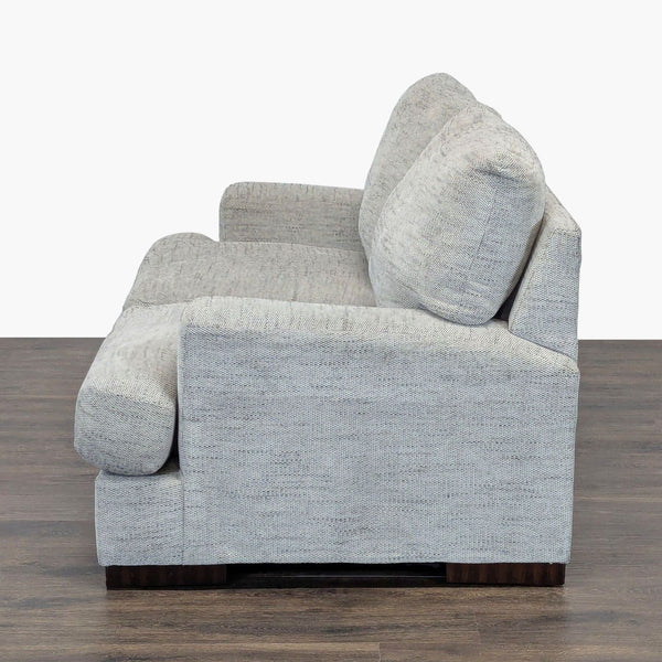 1. Side view of a light gray Ashley Furniture loveseat with plush cushions on dark wood flooring.  