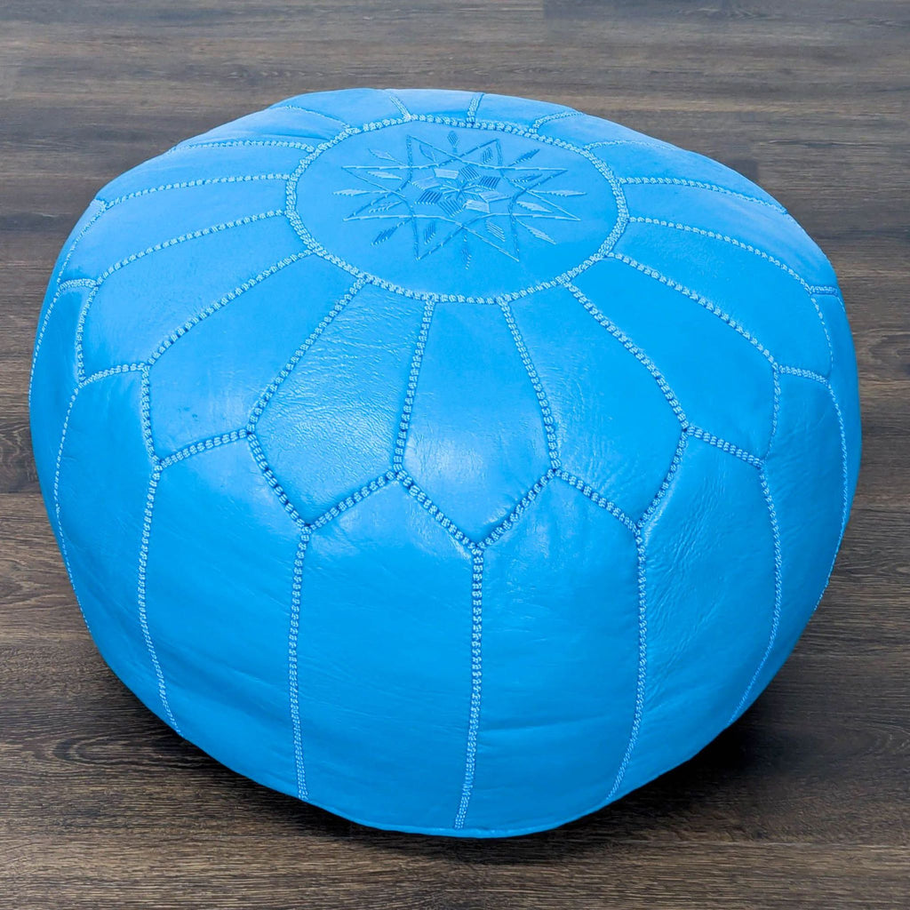 Round Reperch ottoman in vibrant blue leather, featuring star embroidery and geometric stitching on top.