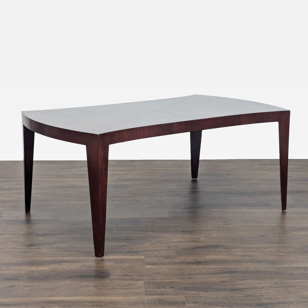 1. Angled view of a New Studio dining table with dark wood legs and a curved rectangular tabletop.