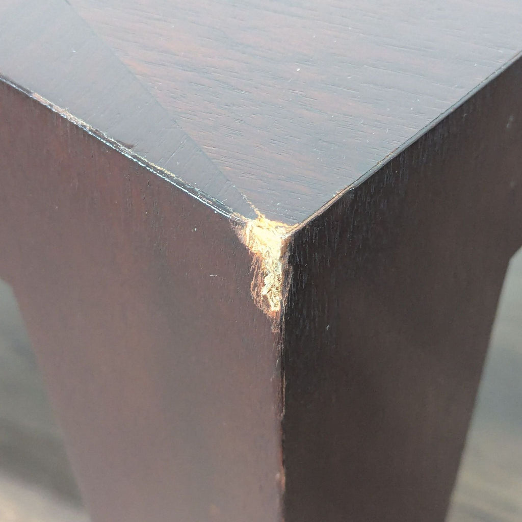 2. Detailed view of a New Studio dining table leg showing a chipped corner with exposed wood.