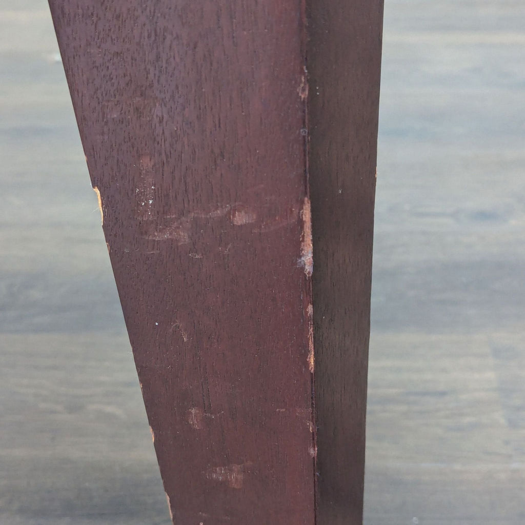 3. Side view of a New Studio dining table leg with scuff marks and scratches along the edge.