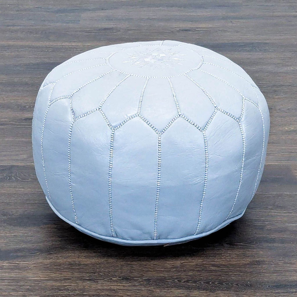 2. Blue leather pouf by Reperch, featuring textured seams and floral embroidery on top.