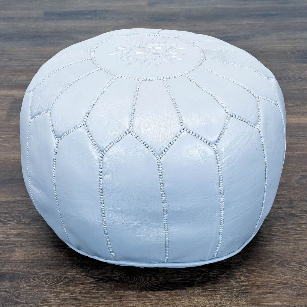 3. Reperch round ottoman in pale blue leather, with detailed stitching and soft, plush appearance.