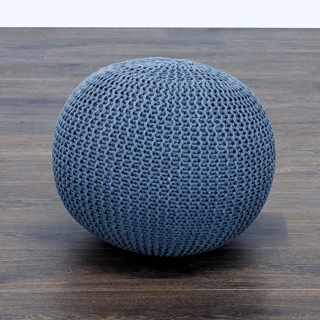 2. Reperch brand blue hand-knitted ottoman, spherical shape, placed on a dark wood surface.  
