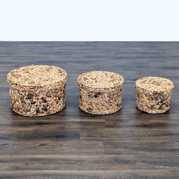 1. Set of three round woven storage baskets with lids by Reperch, arranged by size on a wooden floor.