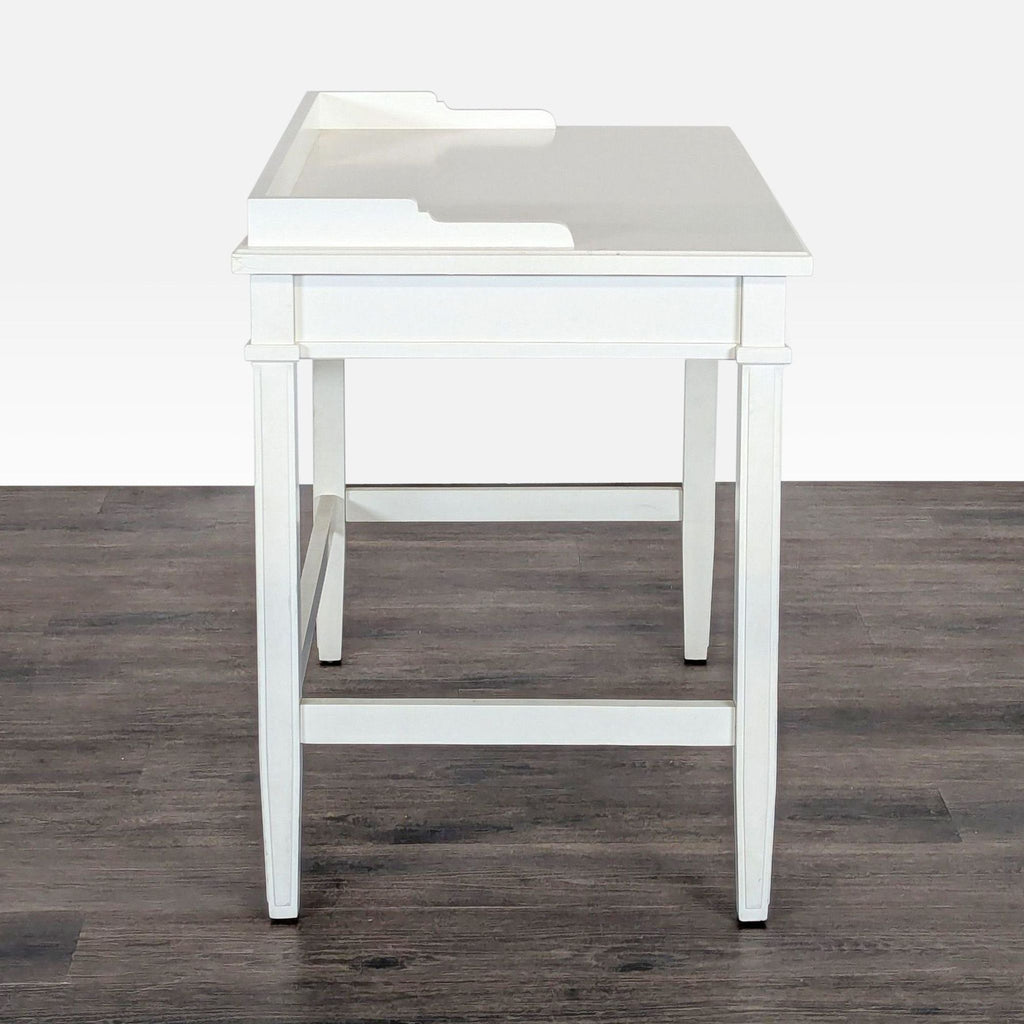 2. Side view of a Crate & Barrel white desk, featuring simple panel legs and a raised desktop edge detail.