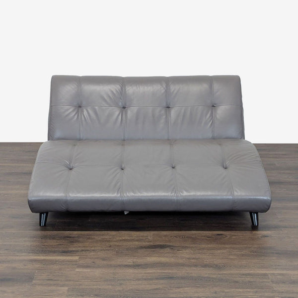 Front view of a modern EQ3 armless lounge sofa in tufted gray leather with curved seat and sleek legs.  