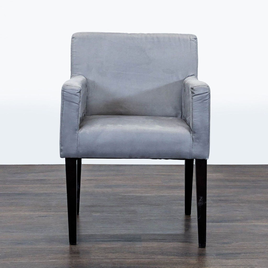 1. Front view of a gray lounge chair by West Elm with a boxy design and black wooden legs on a wooden floor.  