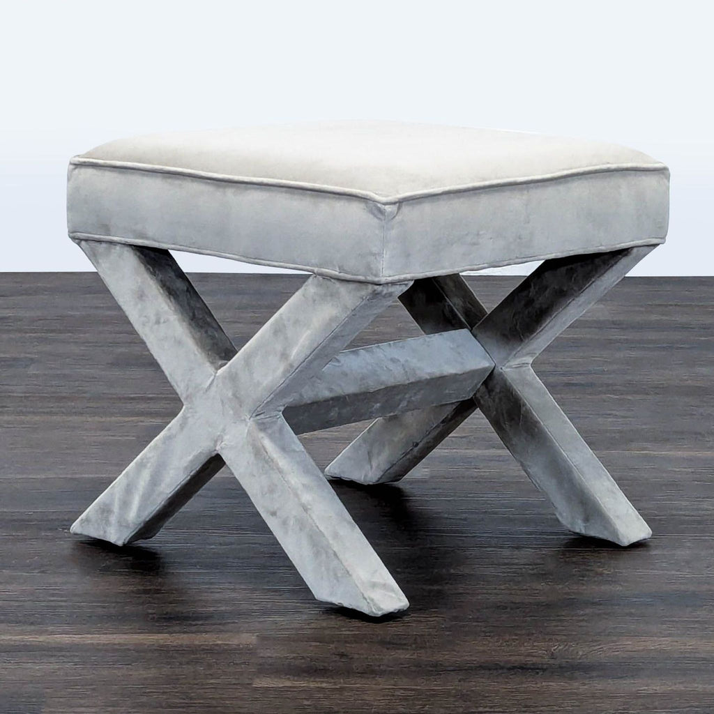 1. Gray West Elm stool with X-shaped legs shown on a dark wood floor, upholstered in soft velvet fabric.