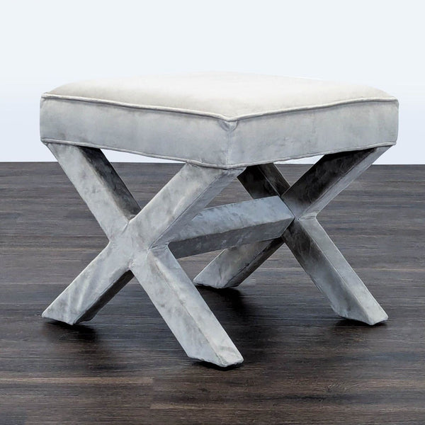 1. Gray West Elm stool with X-shaped legs shown on a dark wood floor, upholstered in soft velvet fabric.