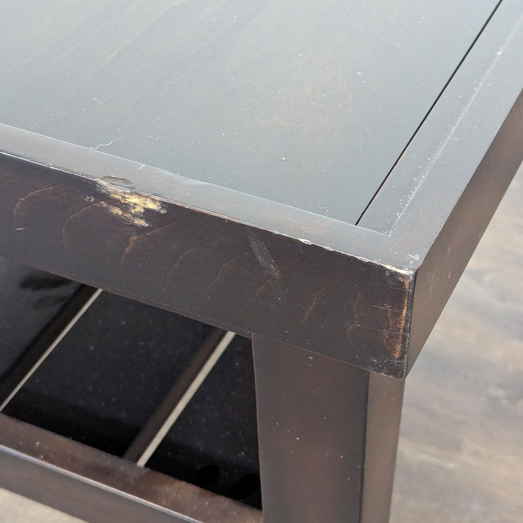 2. Close-up of the Reperch end table corner, highlighting surface scratches and wear on the dark wood finish.  