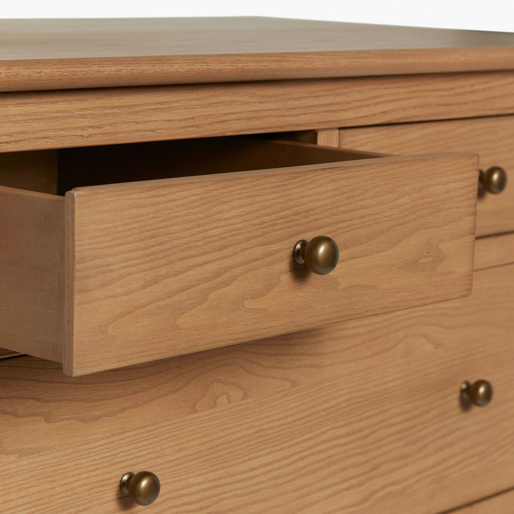 2. Close-up of an open drawer on a Lulu and Georgia dresser, showing wood texture and round brass knob.