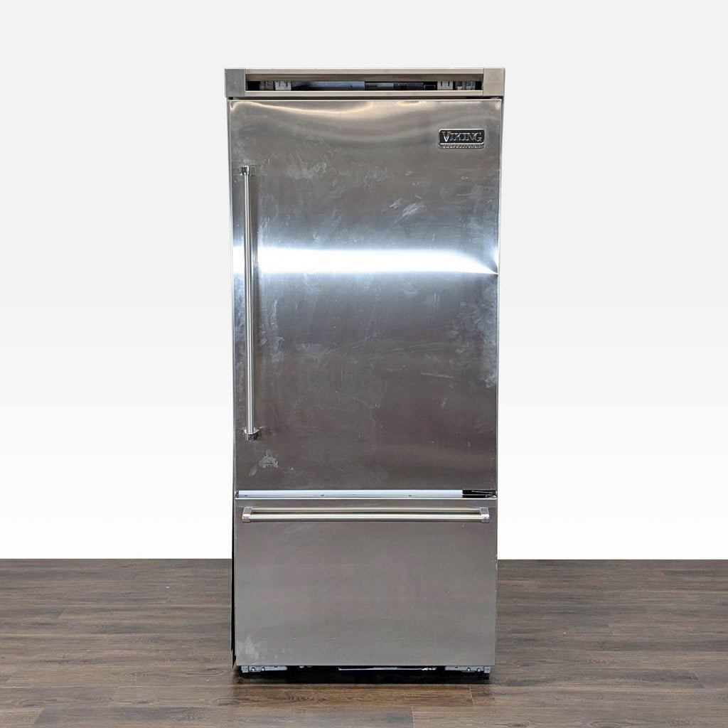 Front view of a Viking Professional stainless steel refrigerator with bottom freezer on wooden flooring.
