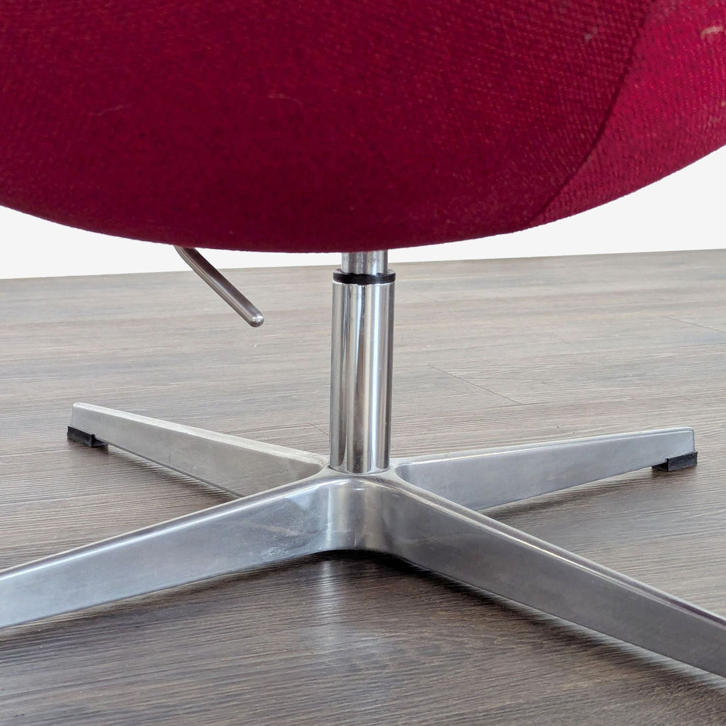 3. Close-up of the sturdy chrome swivel base of the Reperch red lounge chair, highlighting its quality build.