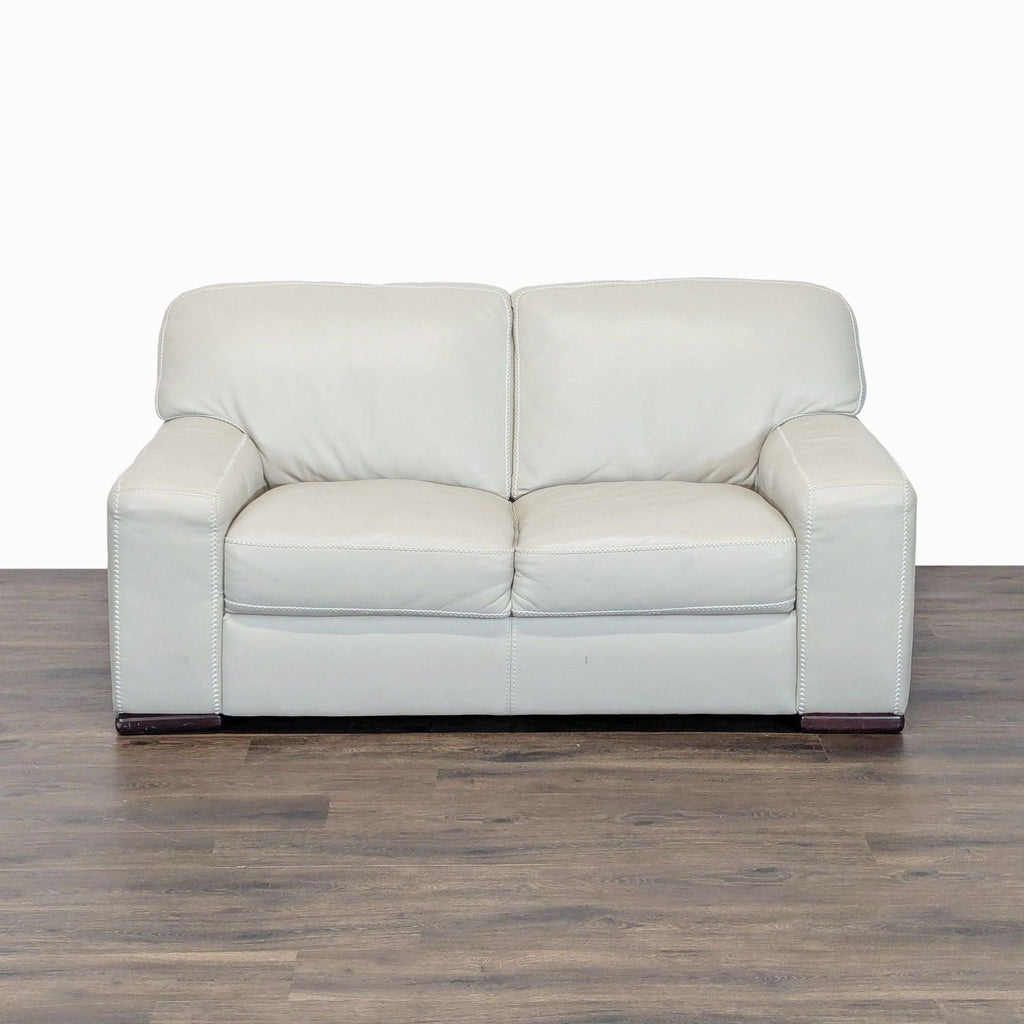 1. Cream leather Reperch loveseat with wide arms, plush cushions, and stable wood feet, shown from the front.