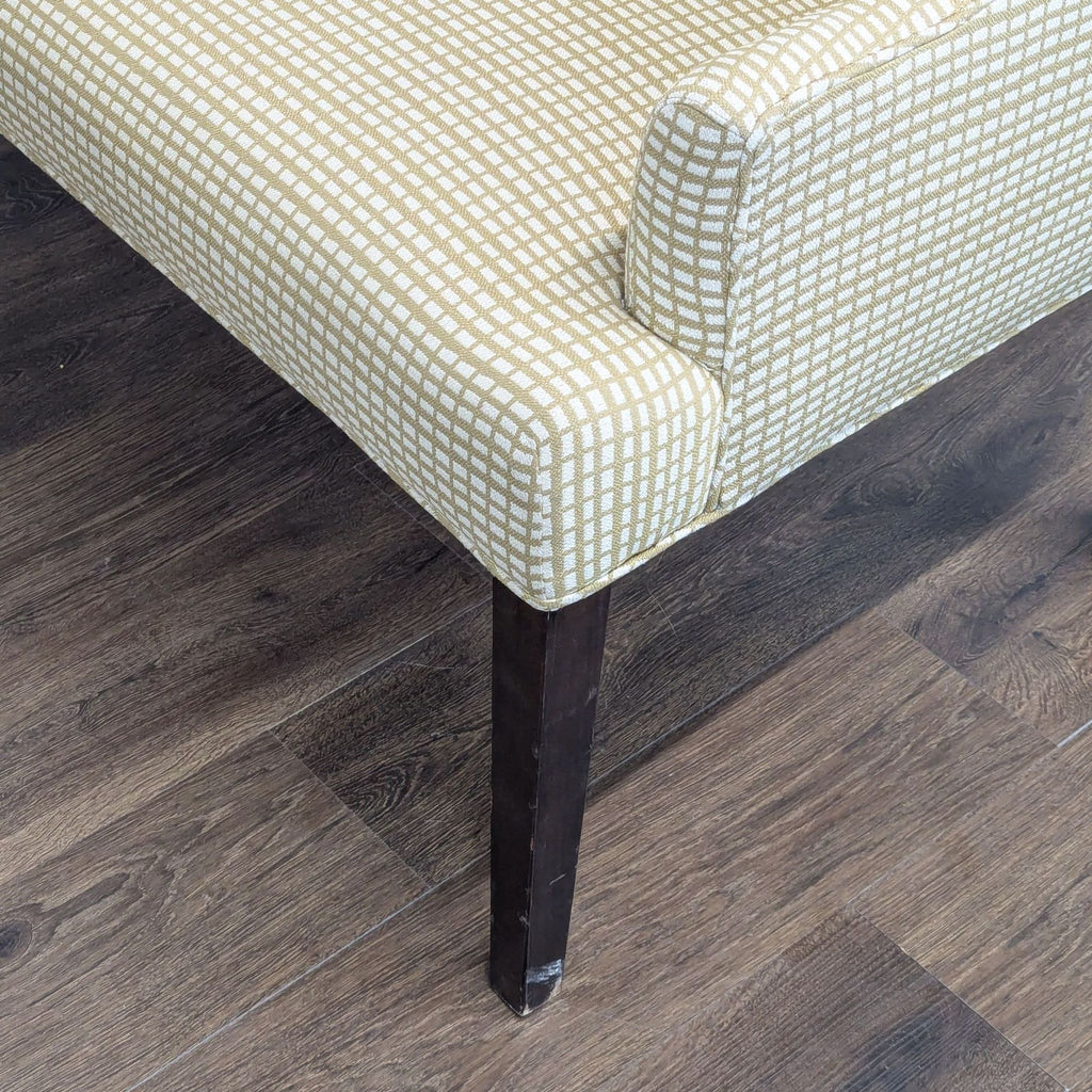2. Close-up of a Reperch bench corner, highlighting beige fabric pattern and dark wooden leg on wood floor.