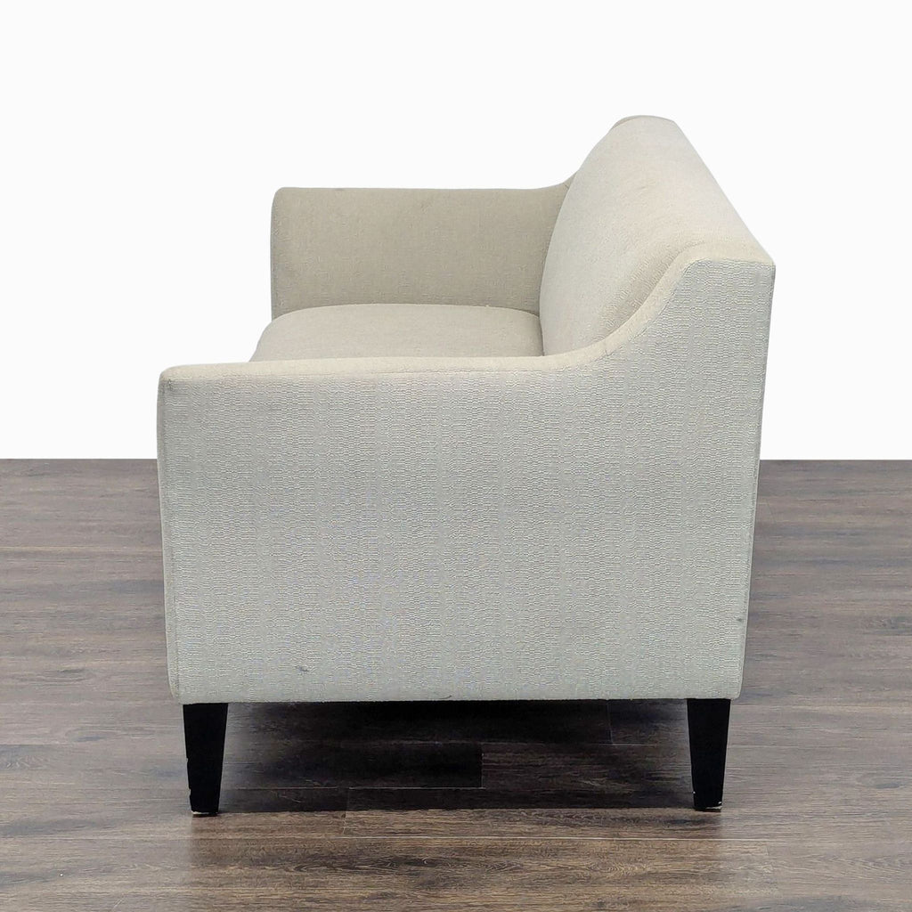 1. Side view of a Shenandoah Furniture loveseat with light-colored upholstery and dark wooden legs on a wooden floor.