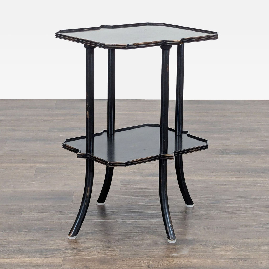 1. Black two-tier Reperch side table with curved legs and scalloped edges, on a wood floor background.